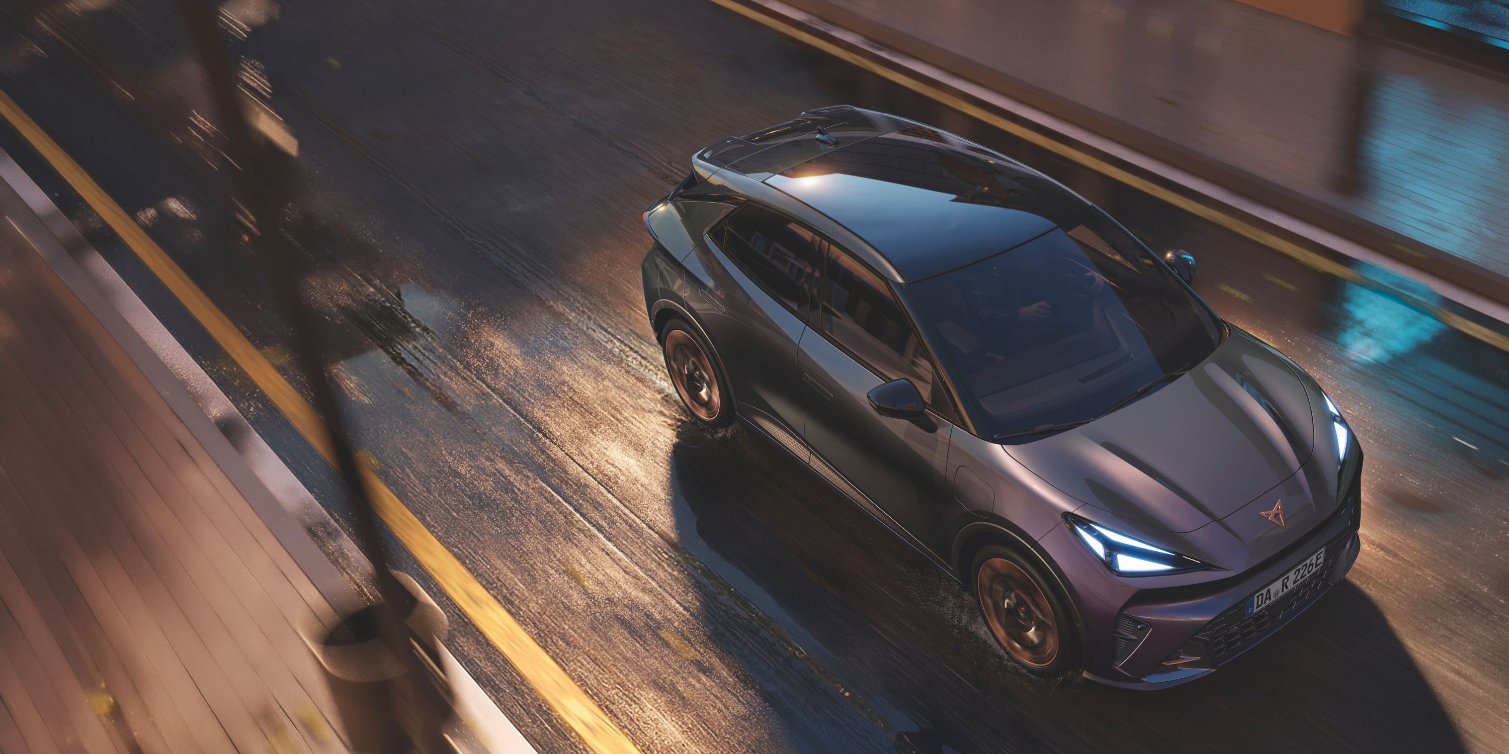 Draufsicht eines dunkelgrauen Cupra Tavascan bei Nachtfahrt auf feuchtem Asphalt.