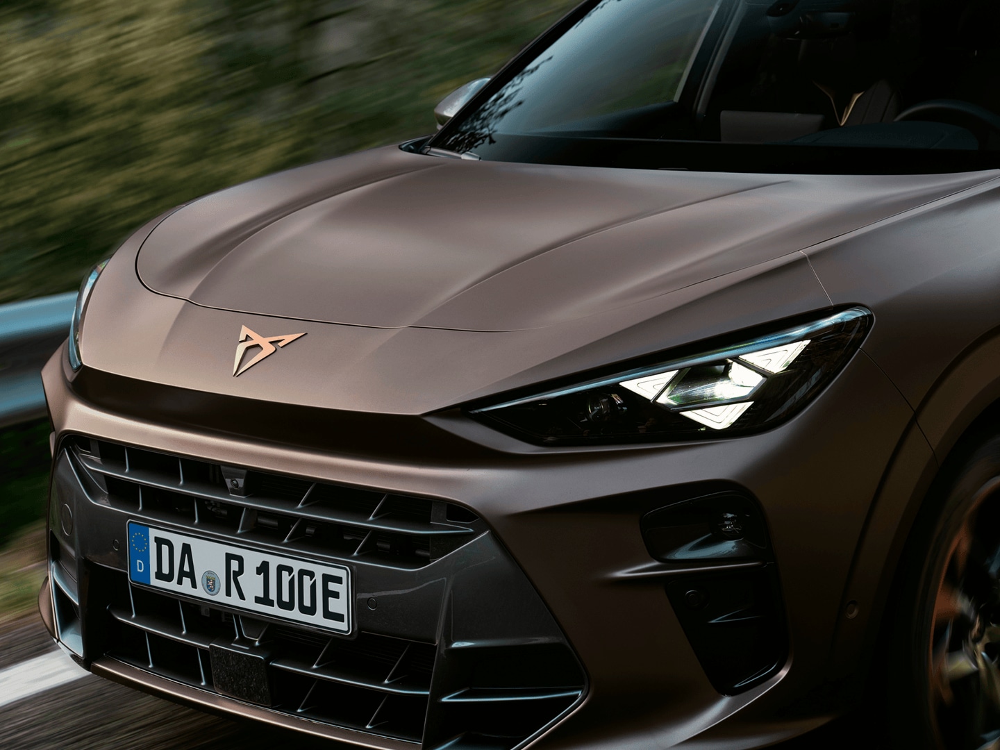 Frontansicht des CUPRA Terramar mit leuchtenden LED-Scheinwerfern und Kupfer-Markenlogo.