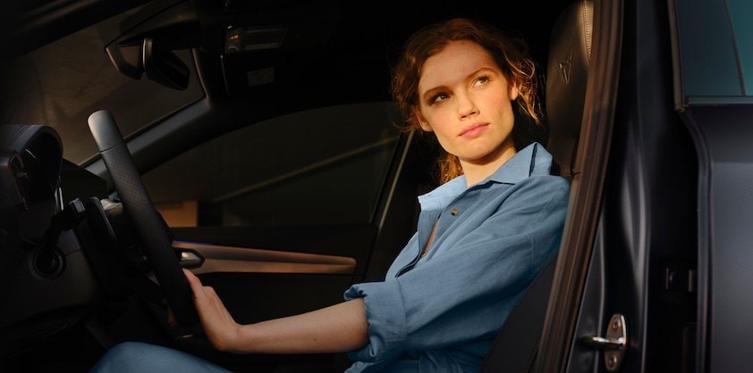 Eine Frau sitzt am Lenkrad eines CUPRA Fahrzeugs.