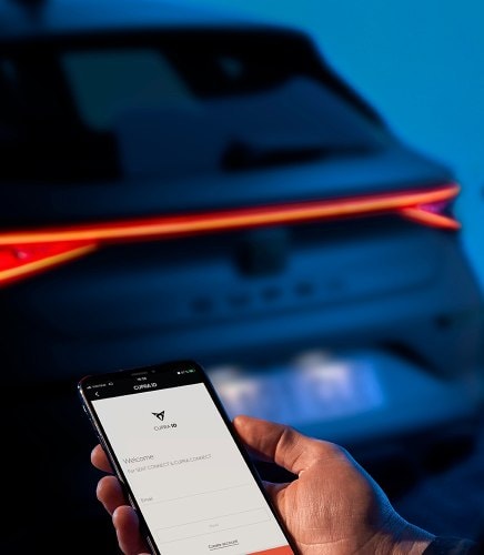 Rückansicht des CUPRA Leon. Im Vordergrund hält jemand ein Smartphone mit der MY CUPRA App.