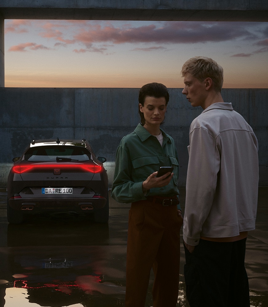 couple-with-mobile-in-front-of-cupra-formentor-dark-camouflage