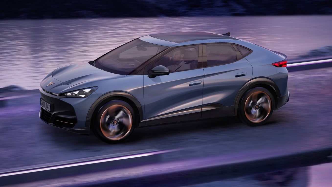 CUPRA Tavascan SUV deportivo 100% eléctrico circulando por carretera junto a un lago al anochecer  