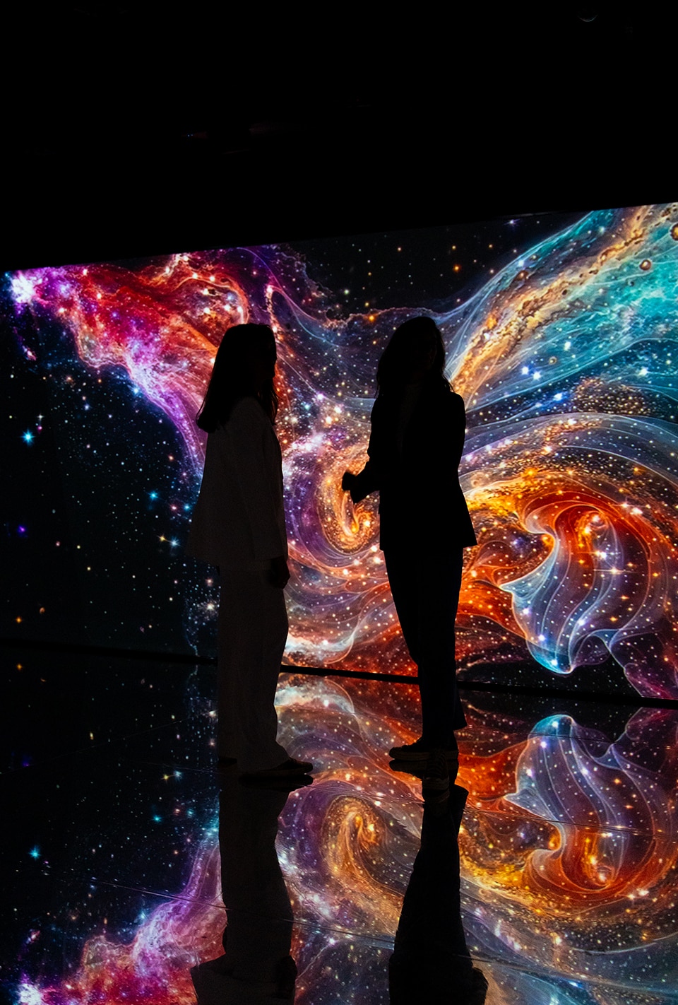 Imagen de una sala inmersiva con dos personas en la oscuridad viendo las estrellas.