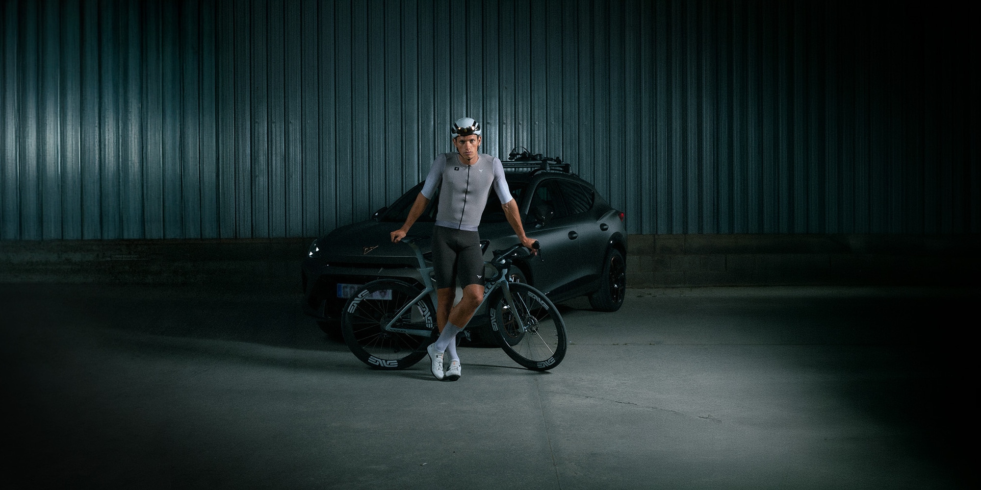 Hombre vestido de ciclista con un CUPRA en el fondo.
