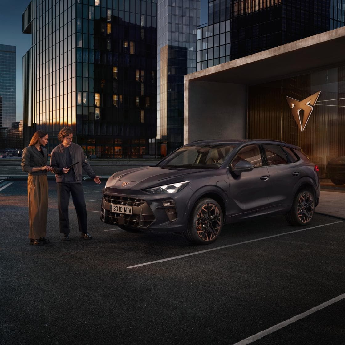 Mujer y hombre charlan junto a un CUPRA Terramar híbrido enchufable de color dark void