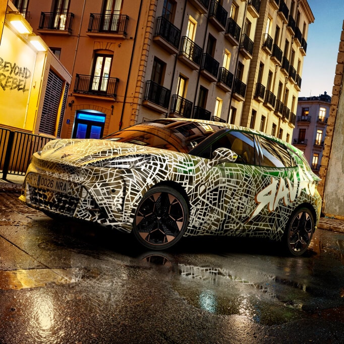 A camouflaged CUPRA Raval at dusk in a city setting