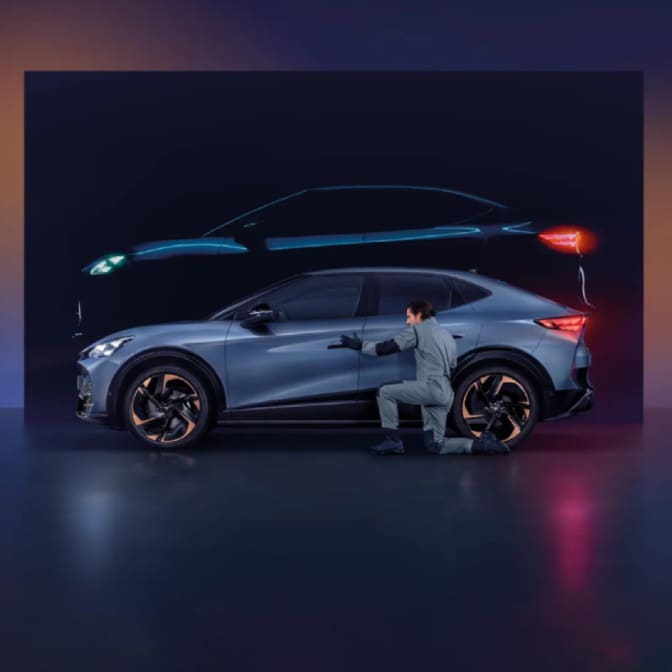 Two people standing between two parked CUPRA Terramar at twilight; a man on the right faces a woman on the left, who is standing near a dark green CUPRA Terramar and a wall-mounted charging station, while a purple Terramar is shown from the rear. 