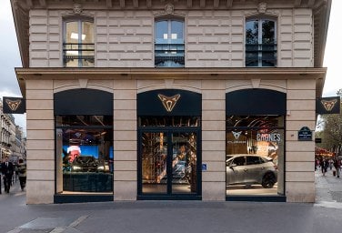 a beige building with a CUPRA logo on top, through the windows we see some CUPRA cars on display