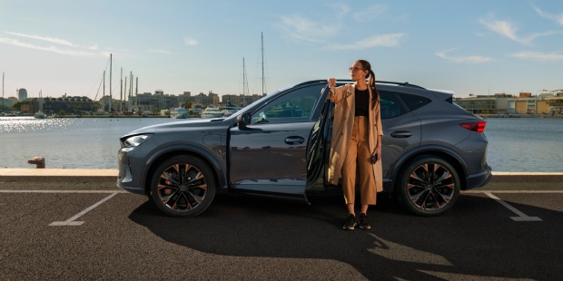 a woman standing next to a CUPRA parked by a port