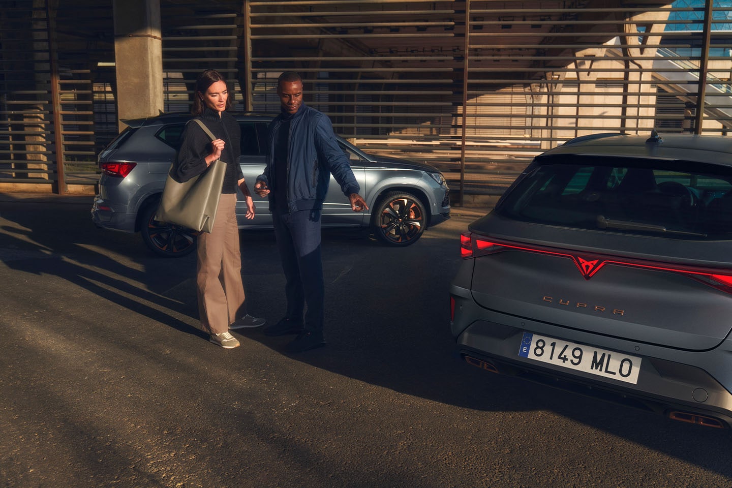 2 people looking at the rear of a CUPRA vehicle with another CUPRA car in the background