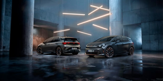 Two CUPRA Born hatchbacks parked in a concrete interior lit by angular light installations.