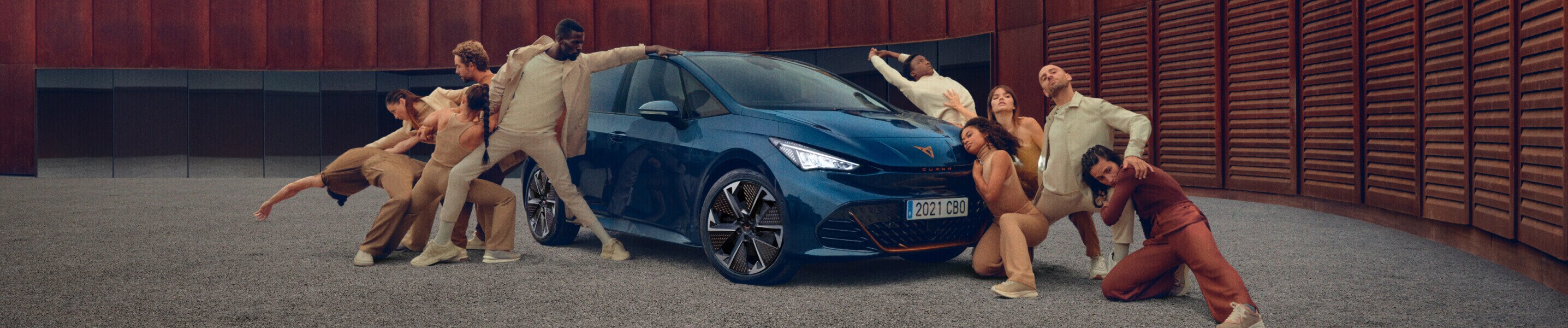 CUPRA Born electric car in Aurora Blue front view, surrounded by people, with a circular structure in the background.