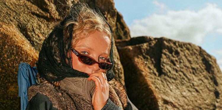 DJ Lana Hayes, On The Pulse finalist, seated outdoors against rocky boulders