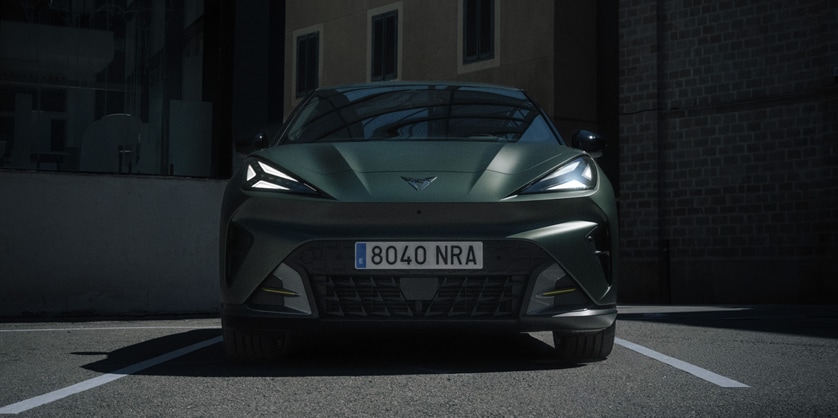 Front view of a matte green CUPRA Raval parked in an urban courtyard in low light
