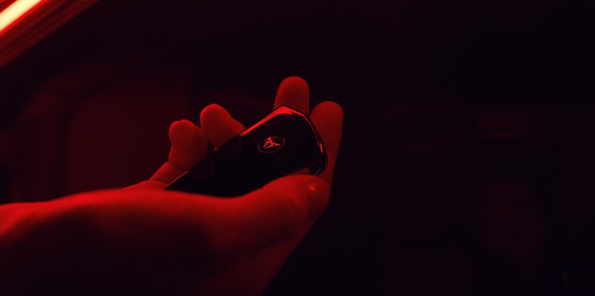 Close-up of a hand holding the CUPRA Raval key fob, lit in red