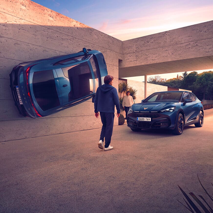 CUPRA Tavascan SUV coupé eléctrico en azul, aparcado frente a una casa moderna, con un  hombre caminando hacia él, lo que simboliza el cambio de coche.