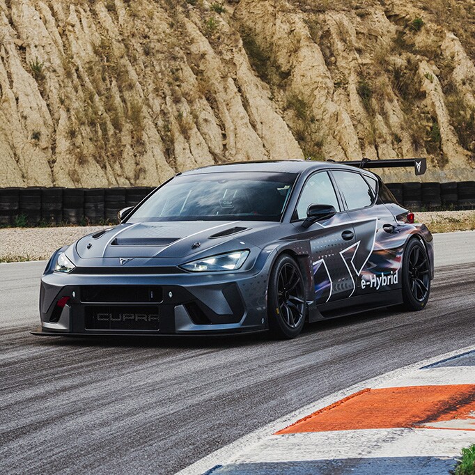 Front-three-quarter view of the CUPRA Leon VZ e-Hybrid Racer driving on a racetrack.