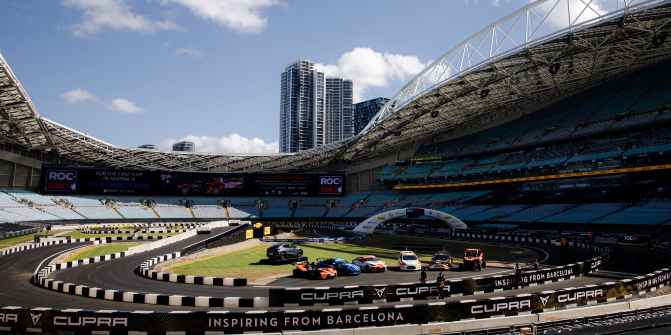 Cupra’s race track, for the 2025 race of champions with cars parked in the middle, surrounded by a blue sky and buildings.