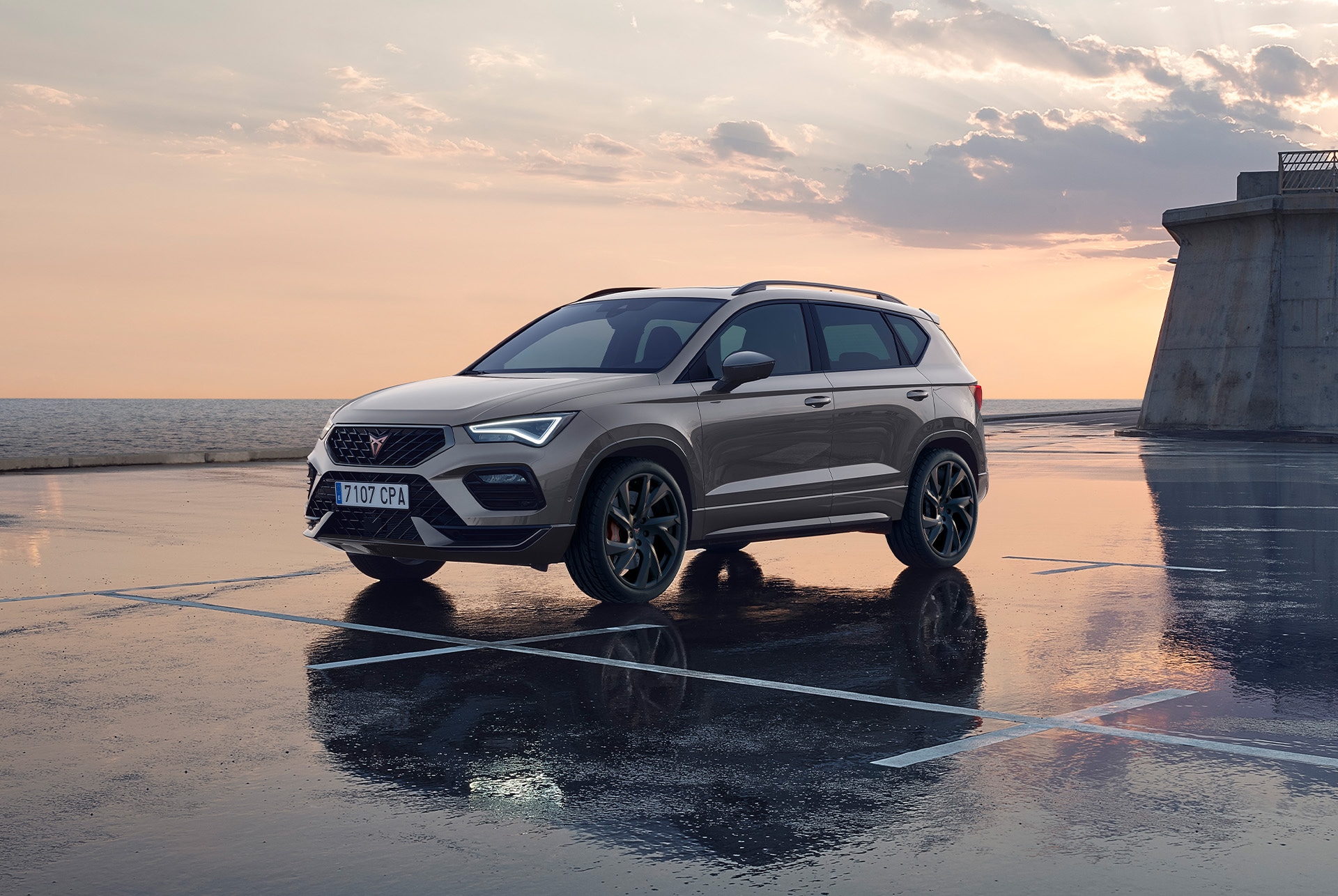 CUPRA Ateca SUV driving on a city road at sunset. The SUV is available with engines in 150hp and 190hp with 4-wheel drive, offering less emissions and fuel consumption.