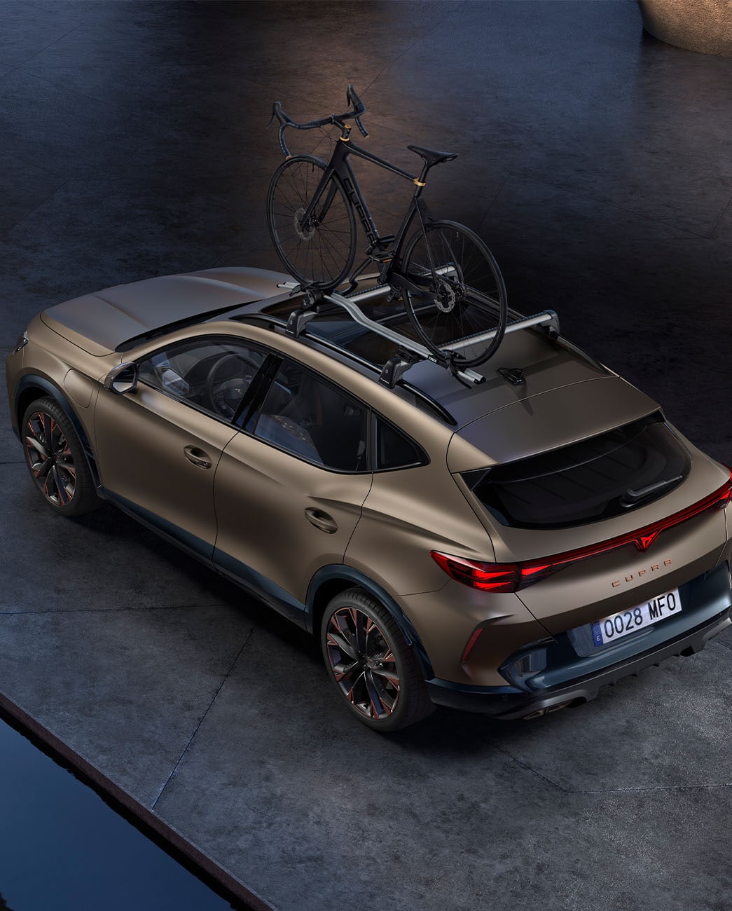 Bird’s eye view of new century bronze matt CUPRA Formentor 2025 with car bike rack accessory, car parked on concrete at dusk.