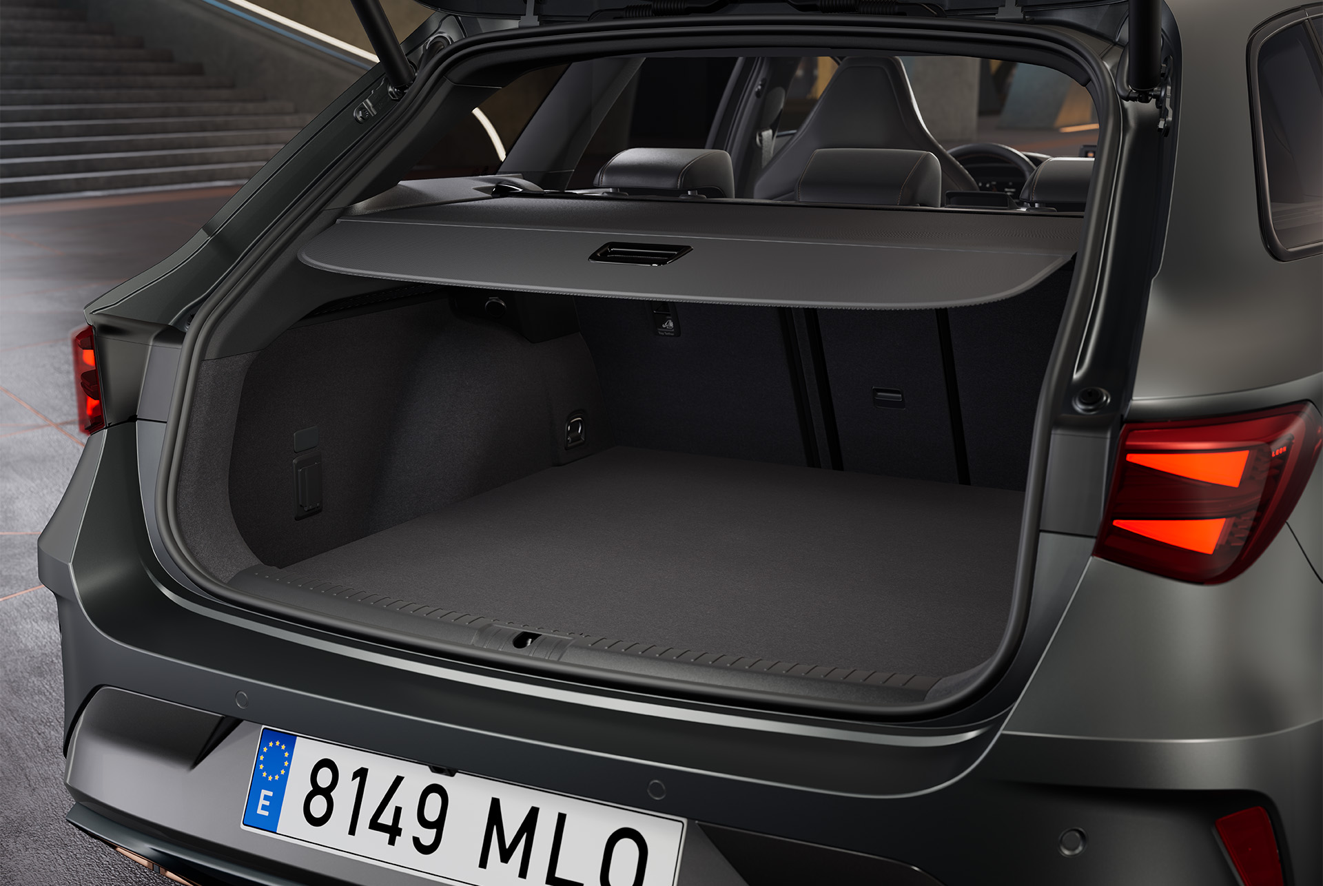 Open boot of a grey Cupra Leon Sportstourer hybrid vehicle, revealing a spacious cargo area with a black interior. The boot holds a bag.
