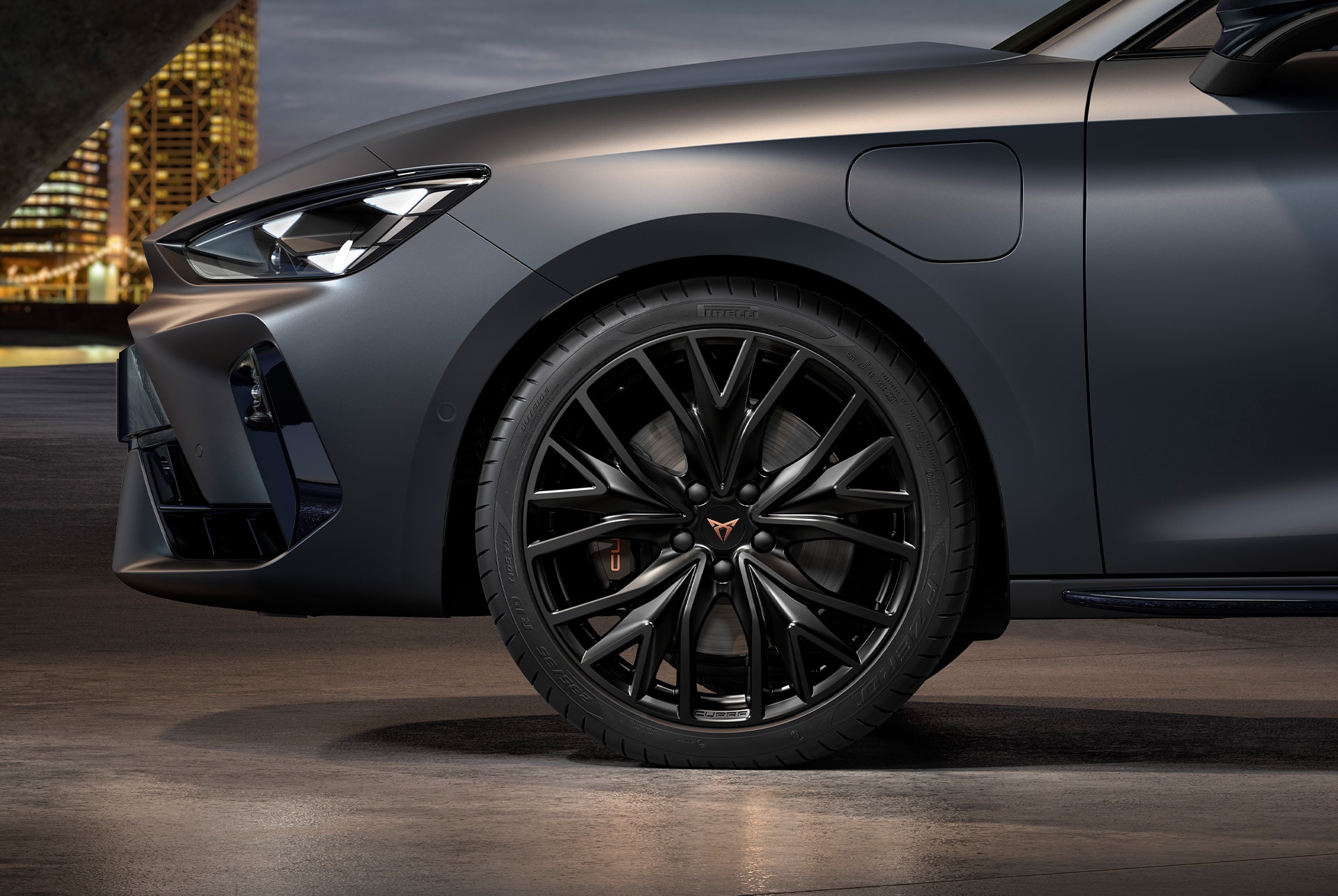 front side view of left alloy wheel in sport black matt for the Cupra Leon Sportstourer, tyres, signature headlights and grey body.