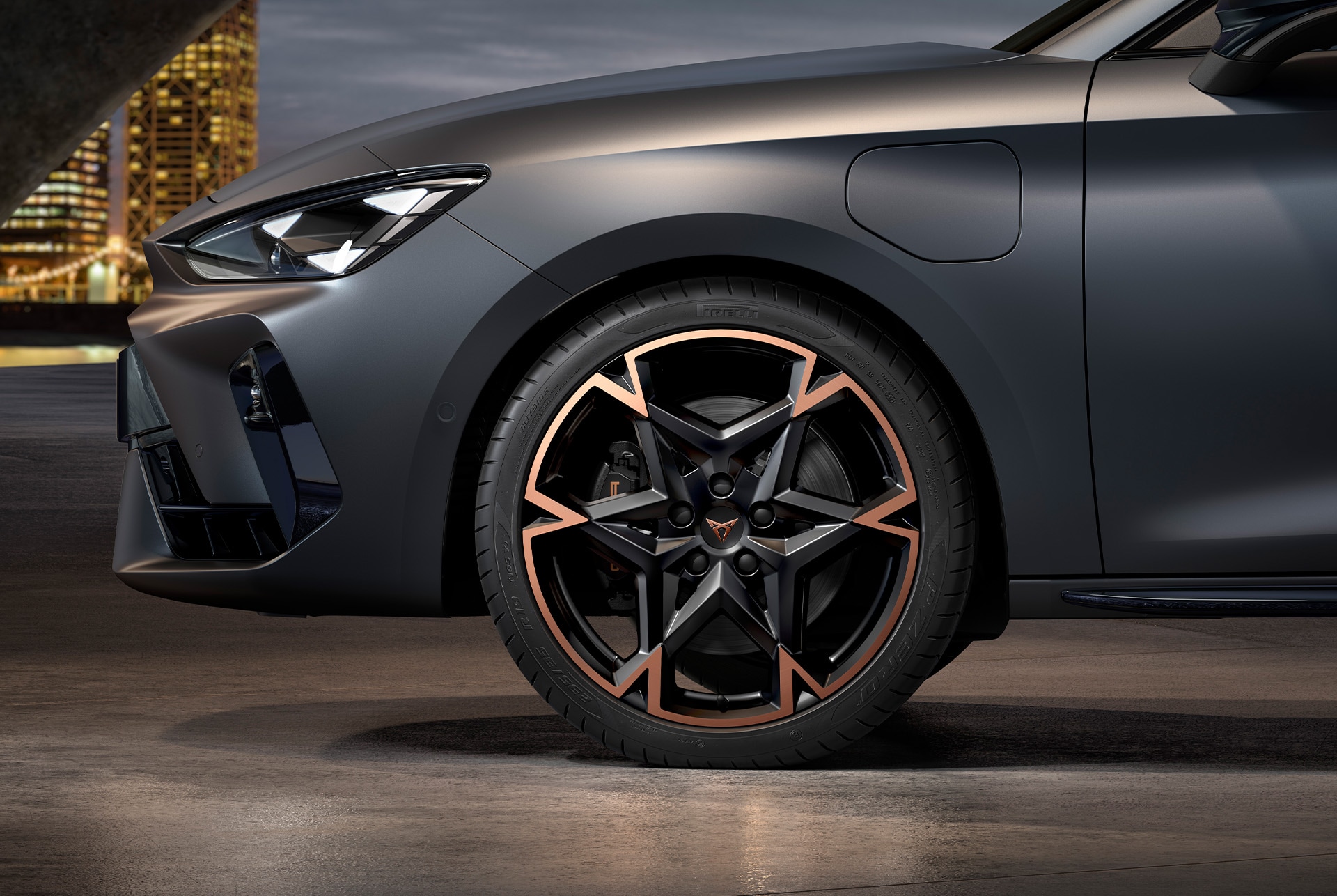 front side view of left machined alloy wheel in black and copper for the cupra leon Sportstourer, tyres, signature headlights and grey body
