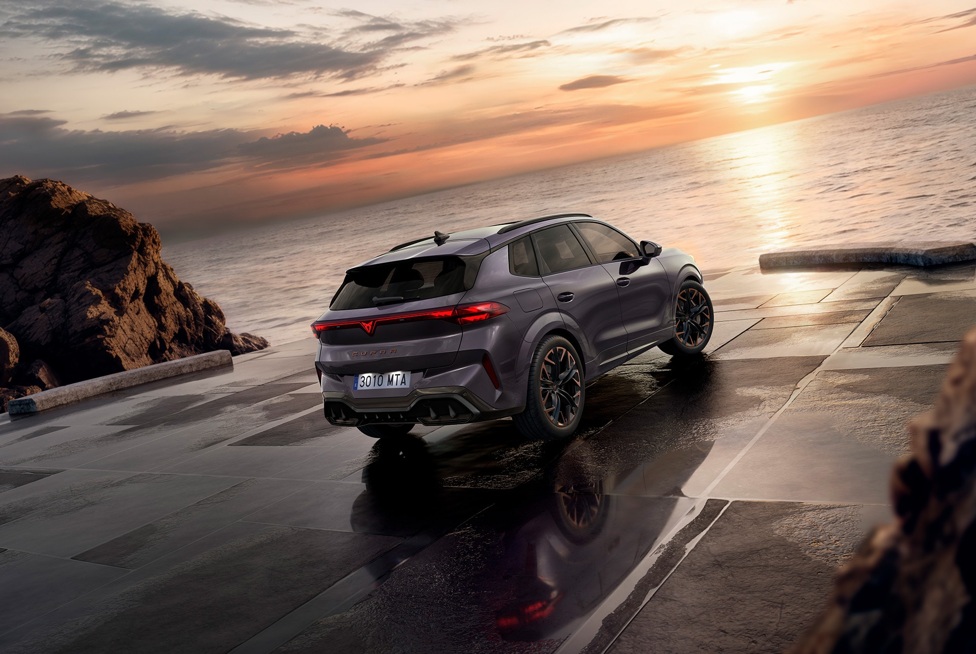 rear view of the CUPRA Terramar 2025 with hybrid tech, parked by the coast at sunset.