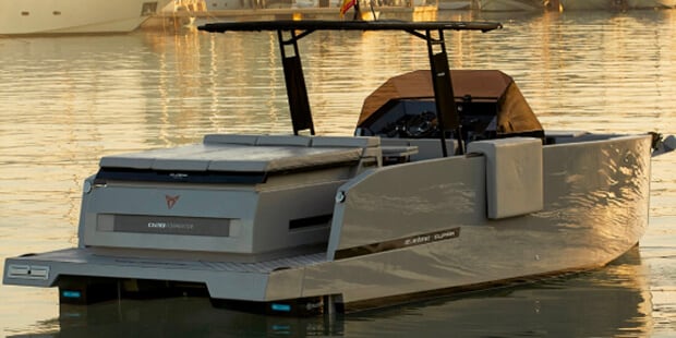 Grey motorboat in marina, cityscape background.