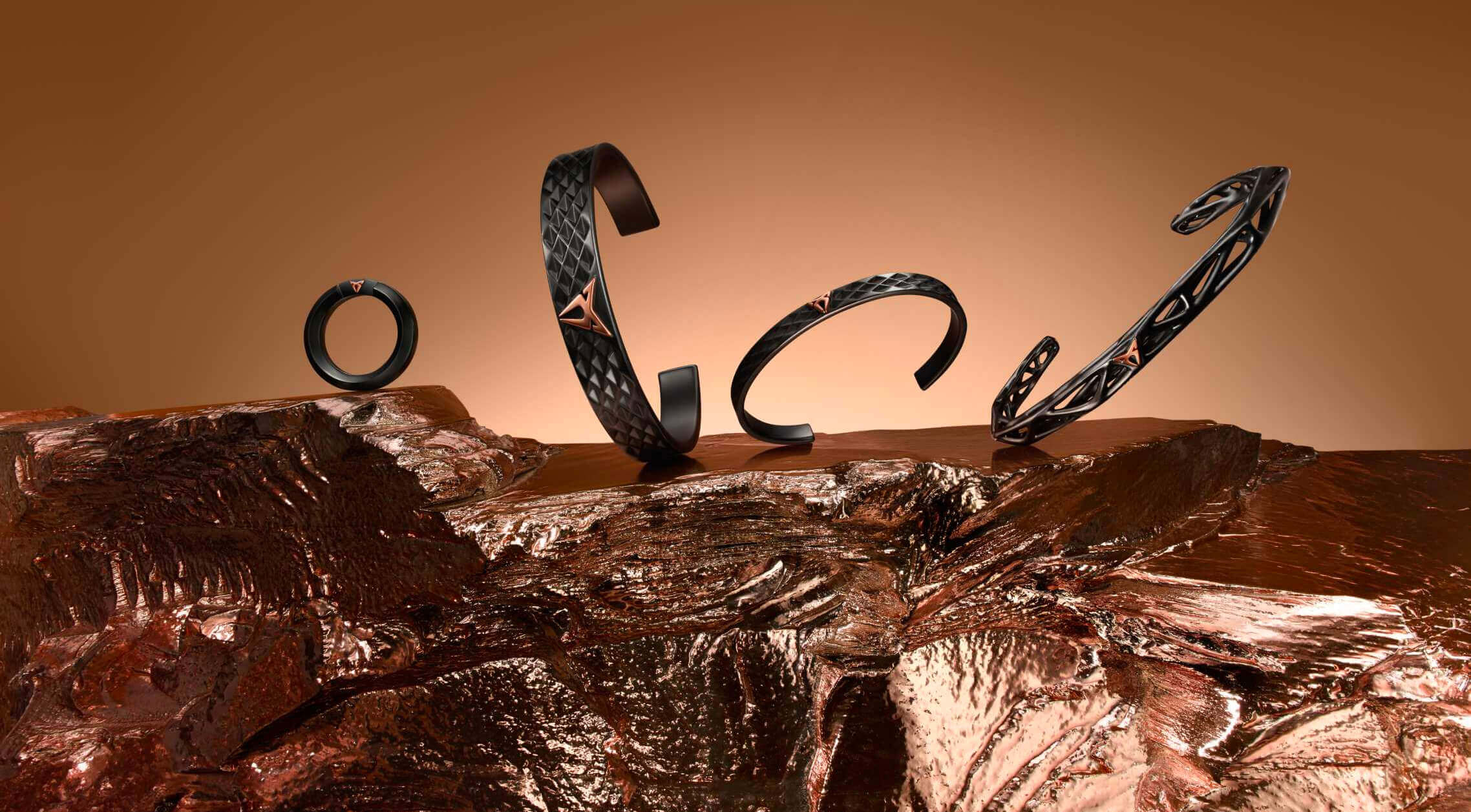 Four black textured bracelets with triangular metal accents, arranged on molten metal or rock.