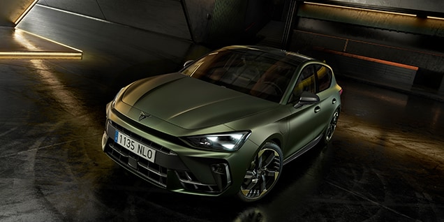 CUPRA Leon, Tribe Edition, in matte green parked in a modern indoor space with ambient lighting and industrial design.