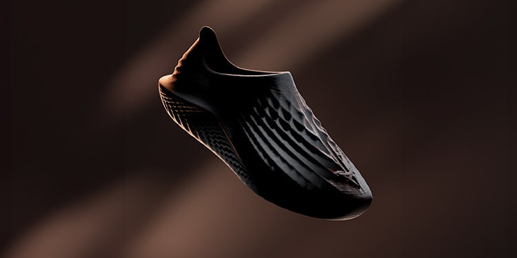 A dark, sleek, futuristic shoe is captured in a dynamic, low-angle shot against a dark background with light streaks. The shoe's design is minimalist, with a single, flowing shape. 