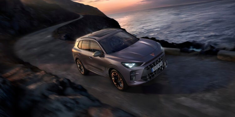 a cupra terramar vehicle navigates a winding coastal road at sunset, capturing eco-friendly performance and adventure against a dramatic, scenic backdrop