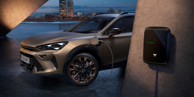 plug-in hybrid electric vehicle, cupra formentor plugged into wallbox, charging at concrete setting with city skyline backdrop