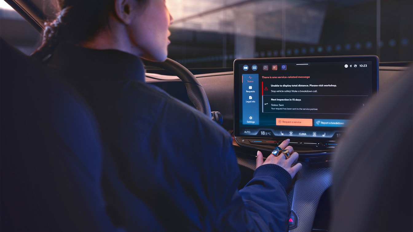 Interior view of a CUPRA car with the driver looking at the infotainment screen, which displays a service-related alert message regarding a vehicle inspection visit.