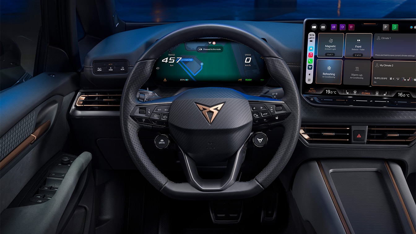 Interior view of the CUPRA Tavascan from the driver's seat, featuring the steering wheel, the digital cockpit displaying a navigation route, and the central infotainment touchscreen.