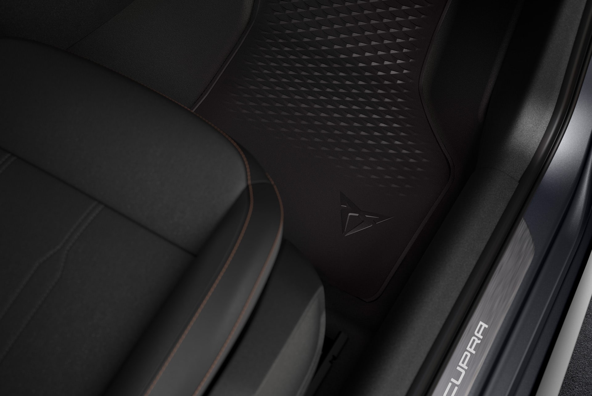 A close-up view of a CUPRA car's interior footwell, featuring a premium black floor mat with a geometric textured pattern and an embossed CUPRA logo.