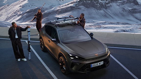 cupra formentor in the mountain. There are three people with skis and snowboard. It highlights the functionality of ski rack when it comes to carry snow accessories.