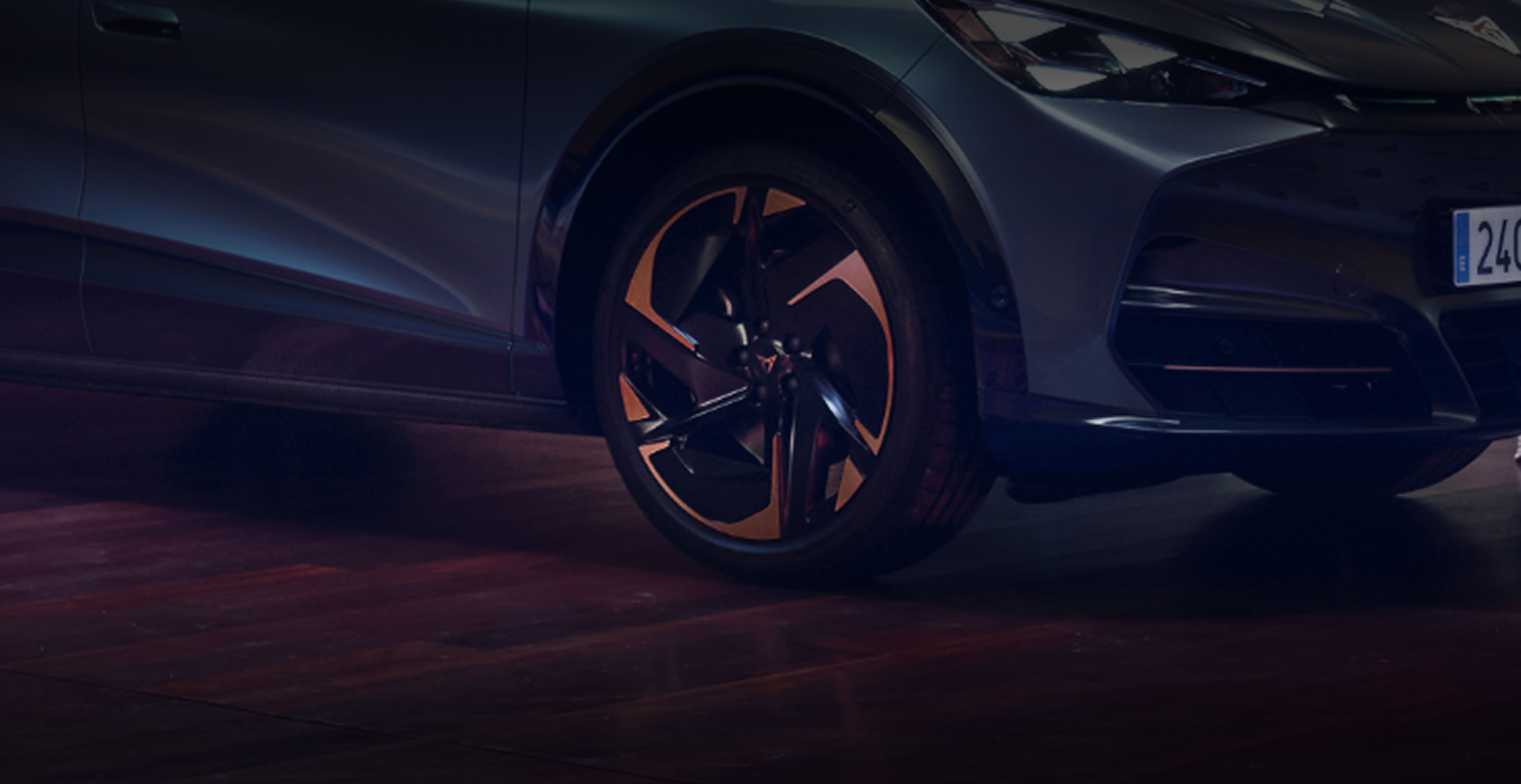 Gros plan sur l’avant d’un CUPRA Tavascan avec jante en alliage et phare LED, dans un atelier automobile.