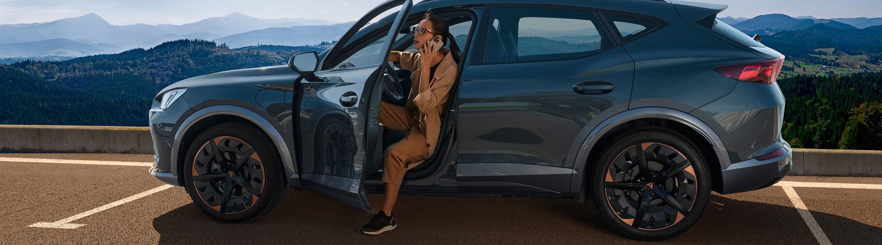 CUPRA Formentor in magnetic grey with the driver stepping out to take in the panoramic view—where bold design meets performance on every journey.