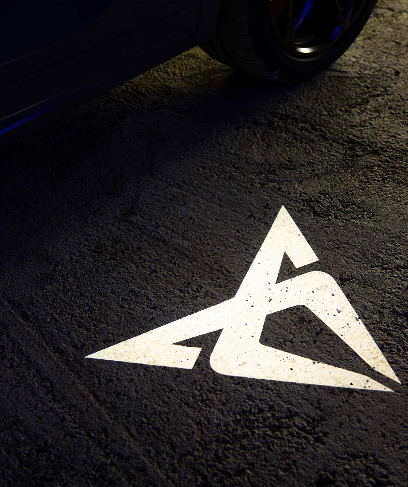 CUPRA Terramar projecting the iconic CUPRA logo onto the dark pavement within a nocturnal urban setting.